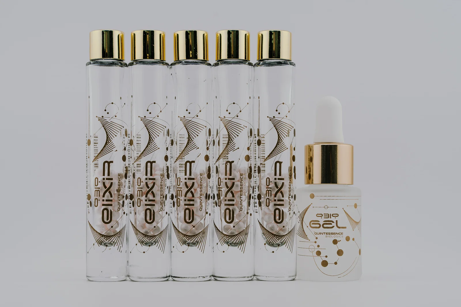 Five QBio Elixir vials in a row beside a gold-collar QBio Gel bottle.